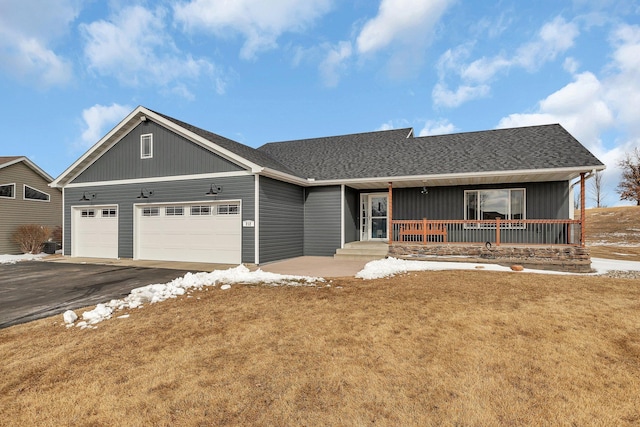 view of front of home with aphalt driveway, roof with shingles, a porch, an attached garage, and a front lawn