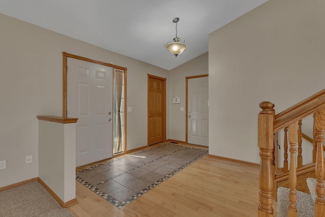 foyer with stairs, vaulted ceiling, baseboards, and wood finished floors