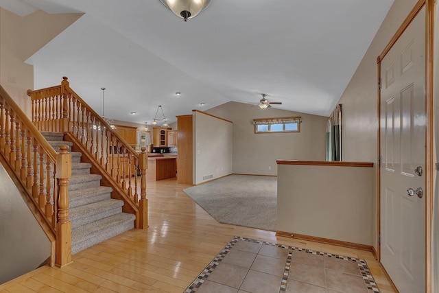 foyer entrance with light wood finished floors, lofted ceiling, ceiling fan, baseboards, and stairs