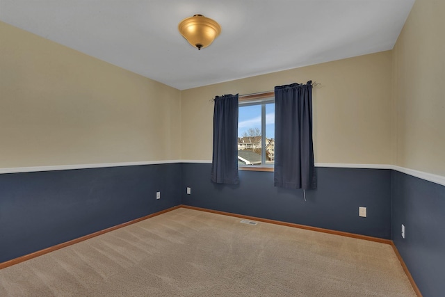 empty room with carpet, visible vents, and baseboards