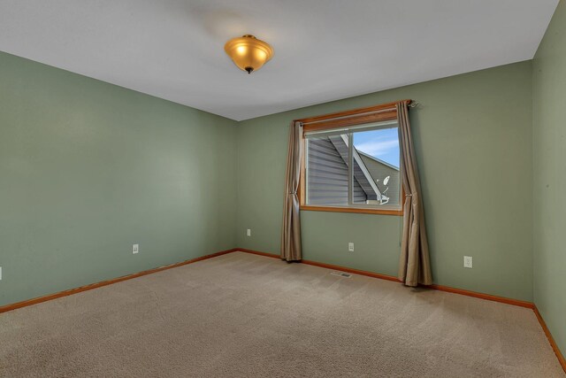 carpeted spare room featuring visible vents and baseboards