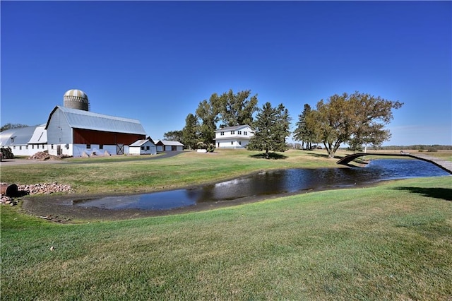 view of yard featuring a water view, an outdoor structure, and a barn