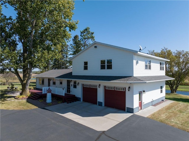 view of front of property featuring a garage, driveway, and a shingled roof