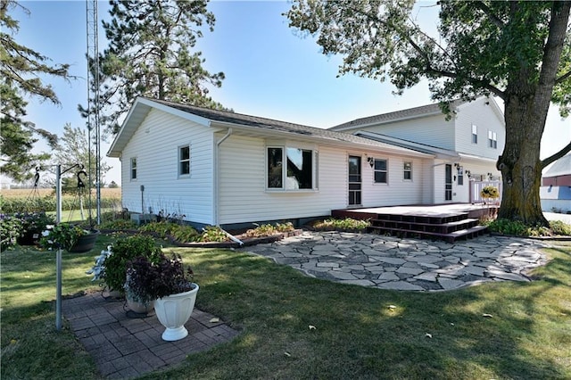 back of property with a patio area, a wooden deck, and a yard