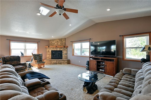 carpeted living area with vaulted ceiling, a stone fireplace, and a healthy amount of sunlight