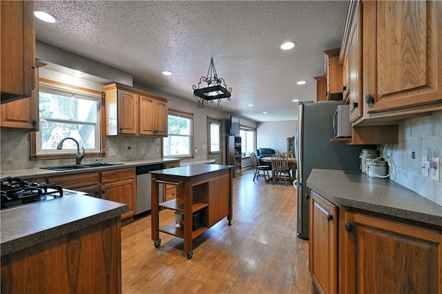 kitchen featuring appliances with stainless steel finishes, dark countertops, brown cabinets, and light wood-style floors