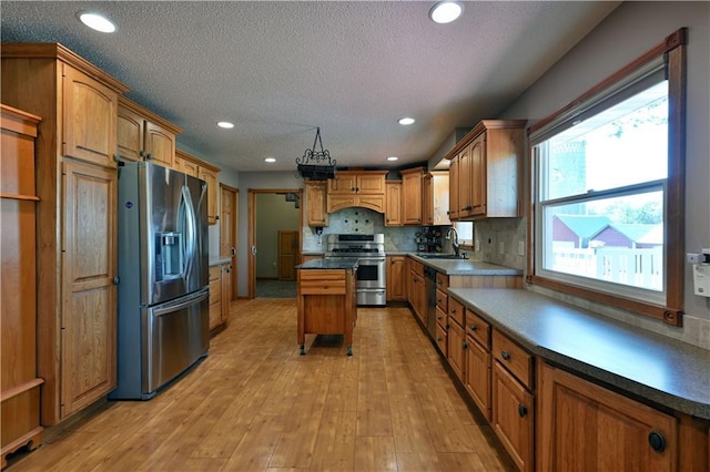 kitchen with light wood finished floors, stainless steel appliances, recessed lighting, tasteful backsplash, and a sink