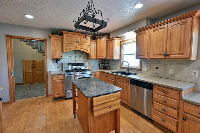 kitchen with a center island, stainless steel appliances, decorative backsplash, light wood-style floors, and a sink