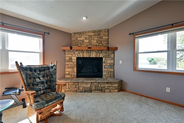 carpeted living room featuring a wealth of natural light, a fireplace, vaulted ceiling, and a textured ceiling