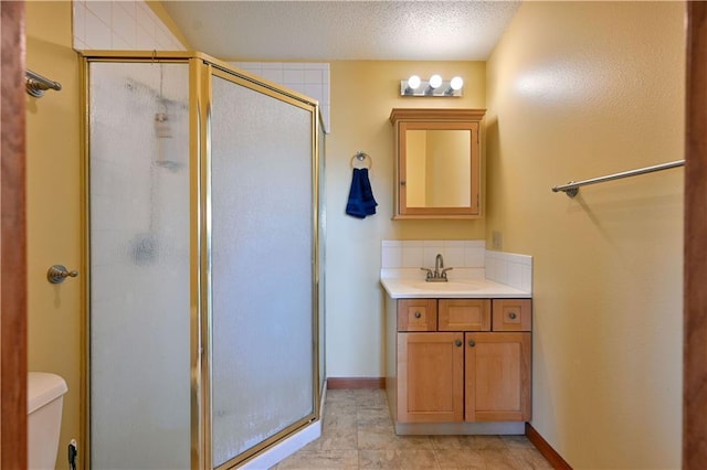 full bath with a stall shower, baseboards, toilet, a textured ceiling, and vanity