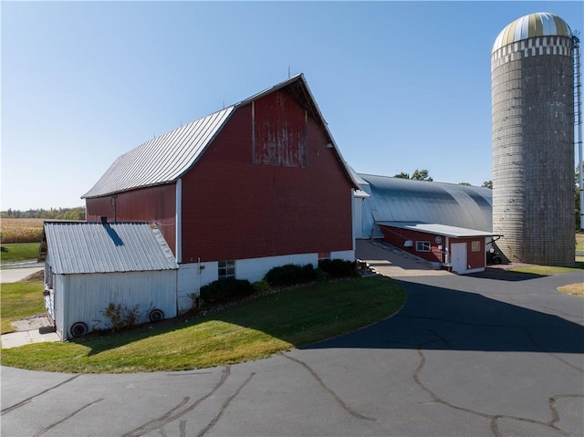 view of home's exterior featuring a yard, an outbuilding, metal roof, and a barn