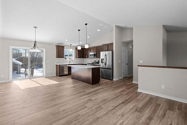 kitchen with a kitchen island, appliances with stainless steel finishes, open floor plan, and light countertops