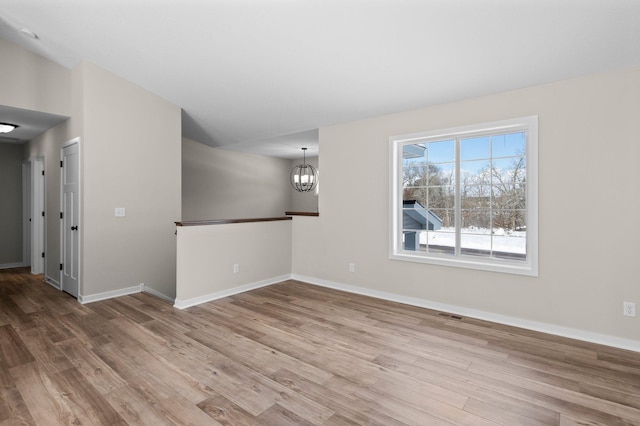 unfurnished room with vaulted ceiling, wood finished floors, and an inviting chandelier