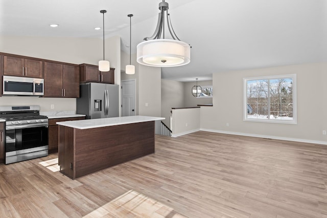 kitchen with light wood finished floors, dark brown cabinetry, a center island, stainless steel appliances, and light countertops