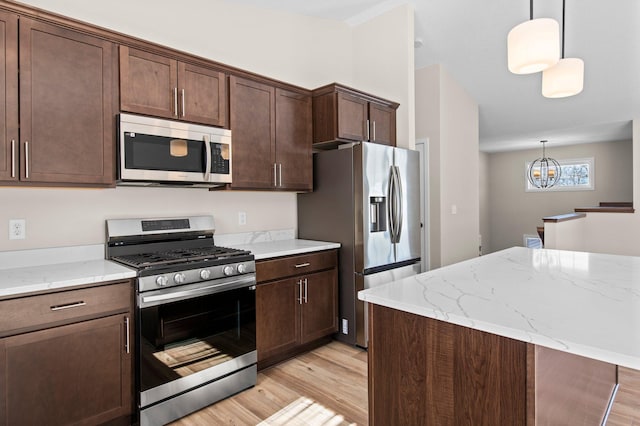 kitchen featuring light wood finished floors, hanging light fixtures, appliances with stainless steel finishes, and dark brown cabinetry