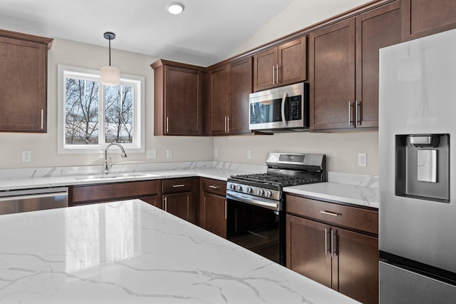 kitchen featuring appliances with stainless steel finishes, hanging light fixtures, light stone countertops, vaulted ceiling, and a sink