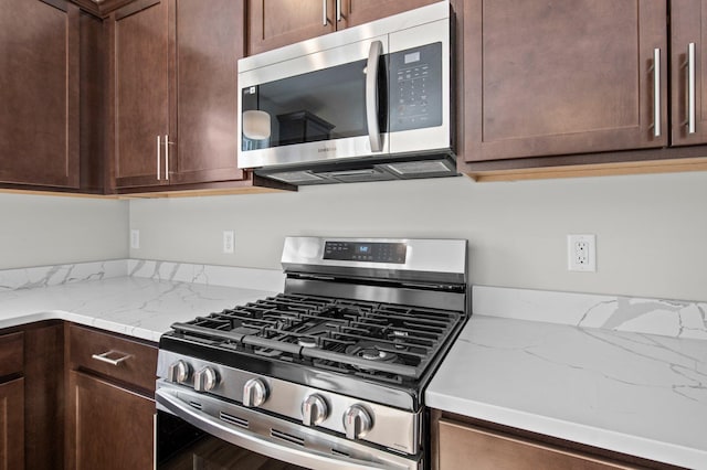 kitchen featuring dark brown cabinets, appliances with stainless steel finishes, and light stone counters