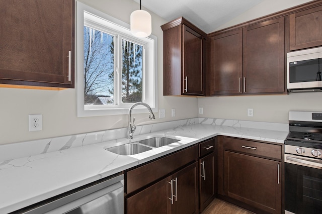 kitchen featuring lofted ceiling, hanging light fixtures, stainless steel appliances, dark brown cabinets, and a sink