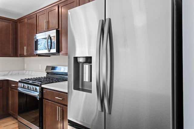 kitchen with appliances with stainless steel finishes, light countertops, and light wood finished floors