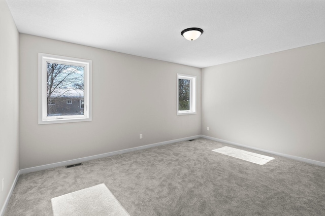 empty room featuring carpet floors, plenty of natural light, and visible vents