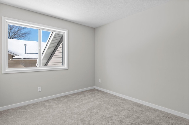 carpeted spare room with a textured ceiling and baseboards