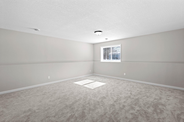 empty room with a textured ceiling, carpet floors, and baseboards