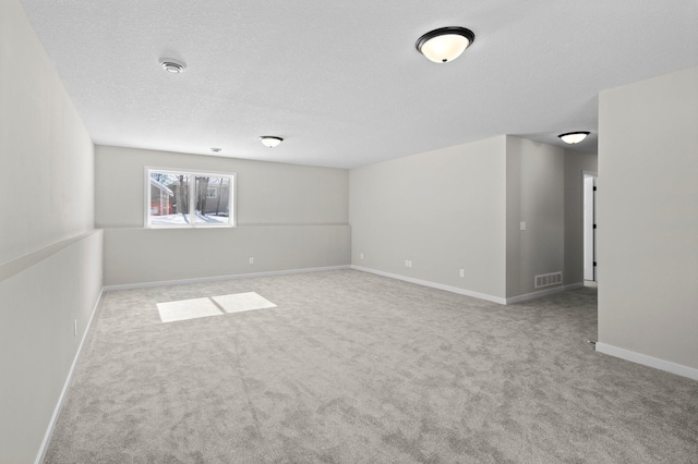 spare room with carpet, visible vents, a textured ceiling, and baseboards