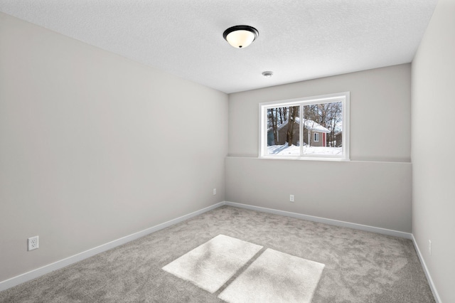 empty room with a textured ceiling, carpet flooring, and baseboards