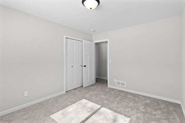 unfurnished bedroom with a closet, visible vents, baseboards, and carpet flooring