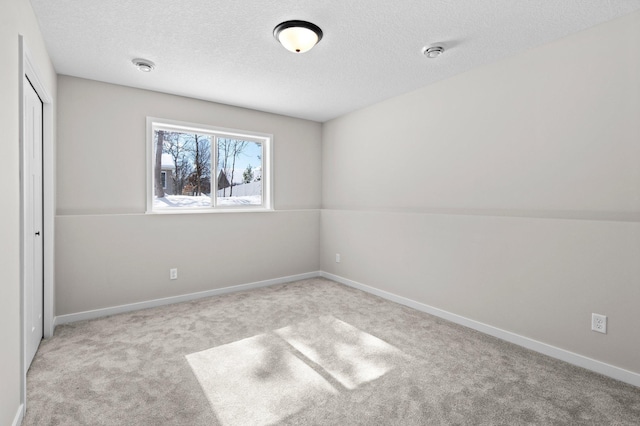 unfurnished bedroom with a textured ceiling, a closet, carpet flooring, and baseboards