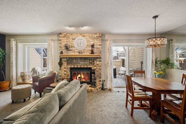 dining room featuring a textured ceiling, carpet, a wealth of natural light, and a brick fireplace