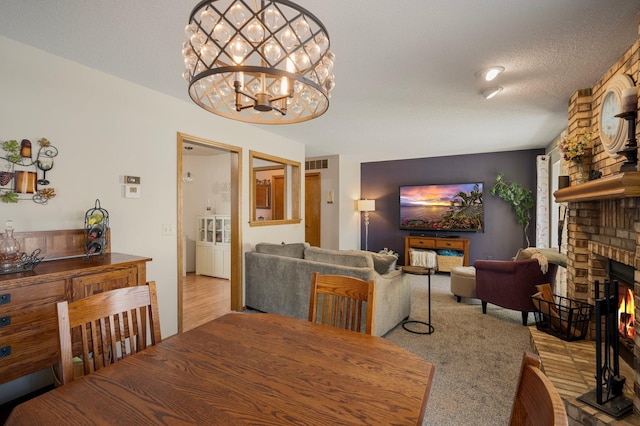 dining area featuring visible vents, a fireplace, a textured ceiling, and an inviting chandelier