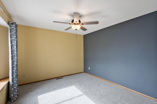 carpeted spare room with a ceiling fan, visible vents, and baseboards