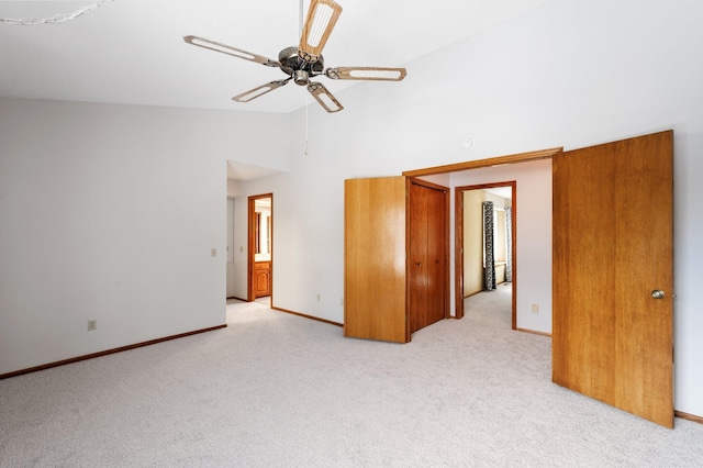 unfurnished bedroom featuring light carpet, baseboards, high vaulted ceiling, and a ceiling fan