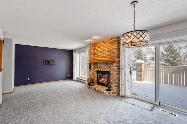 unfurnished living room with a textured ceiling, carpet floors, visible vents, baseboards, and a brick fireplace