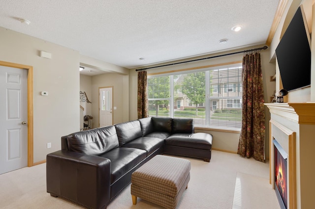 living area with a fireplace with flush hearth, a textured ceiling, carpet flooring, and baseboards