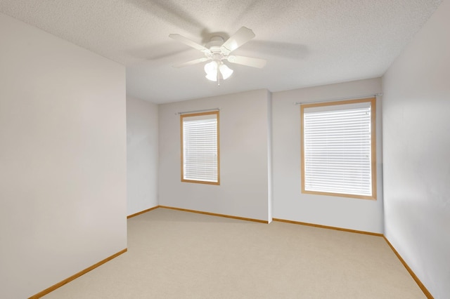 carpeted empty room with ceiling fan, baseboards, and a textured ceiling