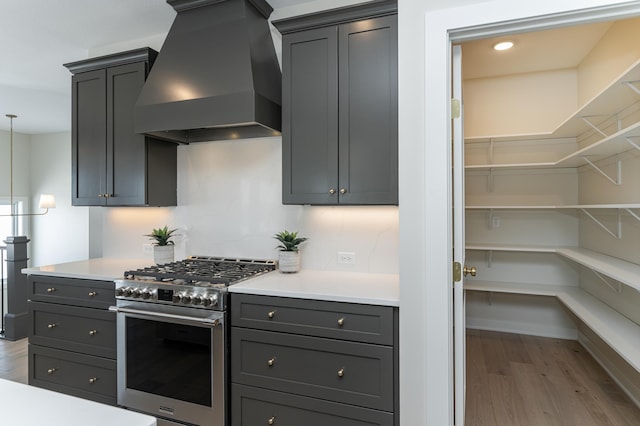 kitchen with light countertops, premium range hood, high end stainless steel range, and light wood-style floors