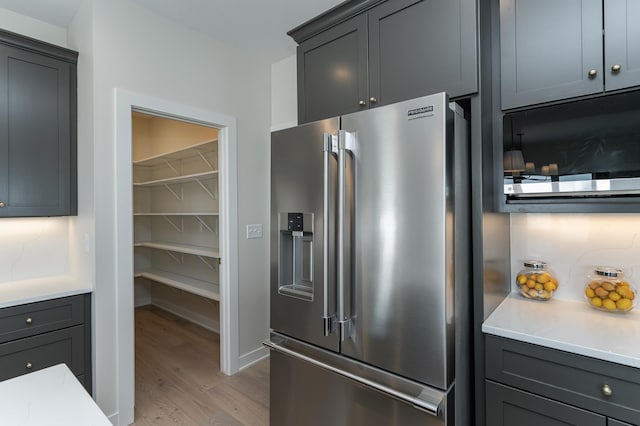 kitchen with gray cabinetry, light countertops, light wood-style floors, and stainless steel fridge with ice dispenser