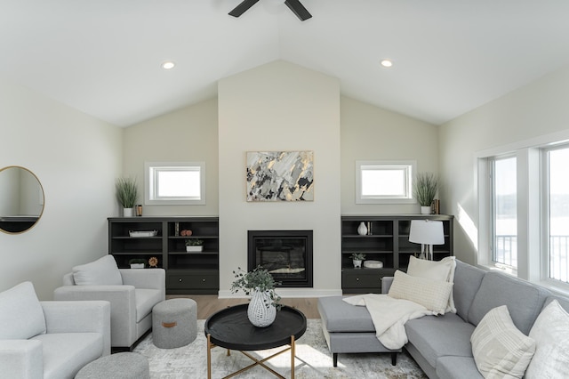 living area featuring a glass covered fireplace, lofted ceiling, recessed lighting, and wood finished floors