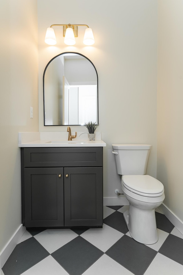 bathroom featuring toilet, vanity, baseboards, and tile patterned floors