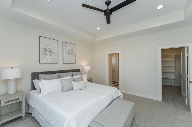 bedroom with recessed lighting, a raised ceiling, a spacious closet, and baseboards