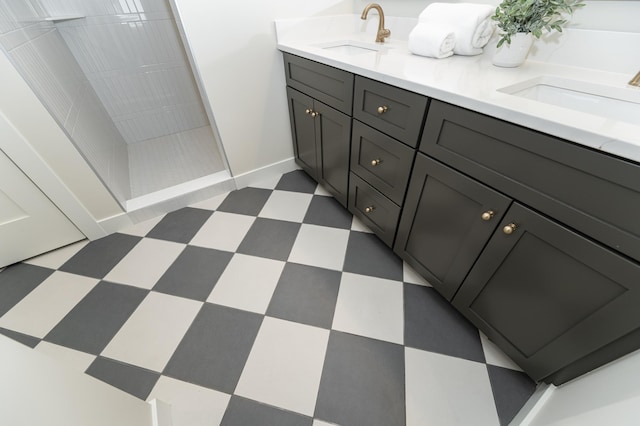 bathroom featuring double vanity, tiled shower, a sink, and tile patterned floors