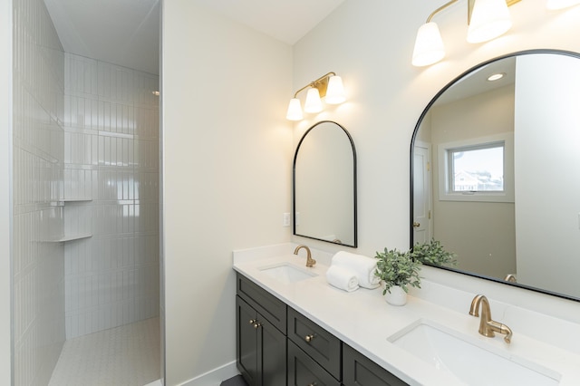 full bathroom with a tile shower, double vanity, and a sink