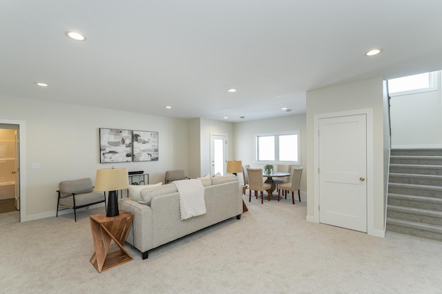 living room featuring recessed lighting, stairs, baseboards, and light colored carpet