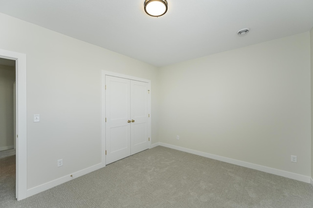 unfurnished bedroom featuring light carpet, baseboards, and a closet