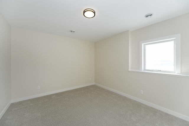 empty room featuring light carpet and baseboards