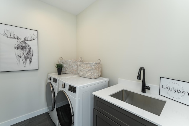 laundry area with cabinet space, baseboards, dark wood finished floors, washer and clothes dryer, and a sink