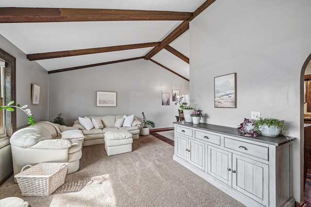 carpeted living area featuring arched walkways, vaulted ceiling with beams, and baseboards