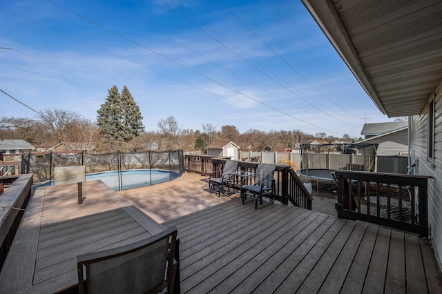 deck with a trampoline, a fenced in pool, and fence